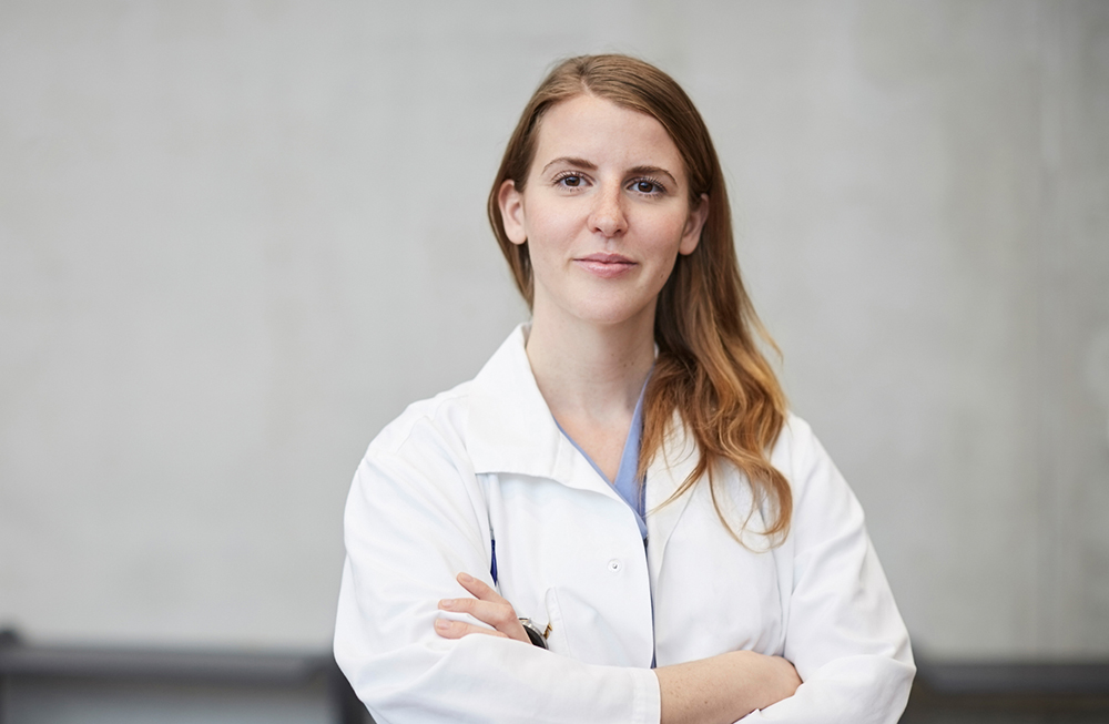 Portrait of confident mid adult female doctor standing with arms crossed against wall at hospital
